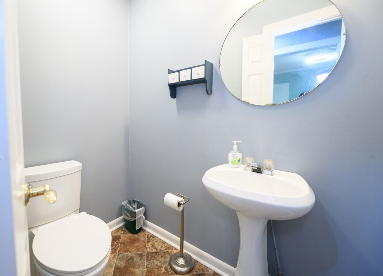 A bathroom with a toilet, sink, and mirror.
