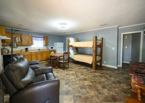 Un espacio habitable compacto con kitchenette, un sofá, una mesa de comedor y una cama nido.