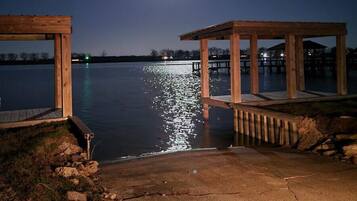 Un muelle de madera se adentra en un lago tranquilo, iluminado por una luna llena en el cielo nocturno.