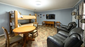 Una sala acogedora con una litera, una mesa de comedor y un sofá de cuero.
