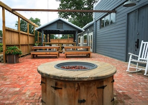 Une terrasse extérieure dotée d’un foyer en bois, de tables de pique-nique et d’un espace salon abrité.