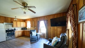 A kitchen with wooden cabinets, a stove, and a ceiling fan. There is a dining area with a table and chairs.