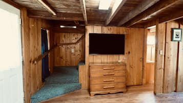 Un interno in legno con una scala, un televisore a schermo piatto montato a parete e un comò in legno.
