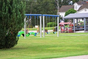 Un parque infantil con columpios y un carrusel rojo.