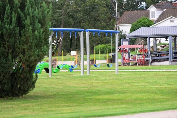 Une aire de jeux avec des balançoires et un manège rouge.
