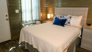 Une chambre à coucher avec un lit, des tables de chevet, un radiateur et une fenêtre avec des rideaux.