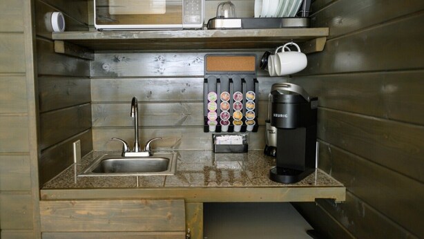 Une petite cuisine équipée d’un four à micro-ondes, d’une machine à café et d’un distributeur de capsules de café.