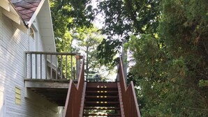 Una escalera de metal que conduce a una casa con fachada blanca y un balcón.