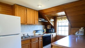 Una cocina con armarios de madera, un refrigerador blanco, una estufa, un microondas y una ventana con vistas.