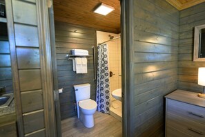 A compact bathroom with a toilet, sink, and shower area. - Serene cabin, relax and recharge! Great Internet! (Lake Village)