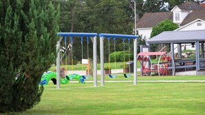Une aire de jeux avec des balançoires et un manège rouge.