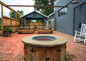 An outdoor patio with a wooden fire pit, picnic tables, and a covered seating area. - Serene cabin, relax and recharge! Great Internet! (Lake Village)