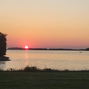 A sunset over a calm body of water with a boat in the distance.