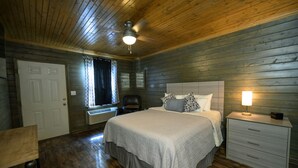 Un dormitorio con cama, mesita de noche, silla y ventilador de techo.
