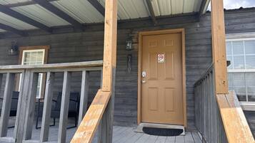 Een houten chalet met een veranda, een deur met een ‘Niet roken’-bordje en een klein raam.
