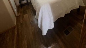 Een slaapkamer met een bed, een raam, een nachtkastje en een lamp.