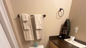 Een badkamer met een toilet, een houten wastafelmeubel en een handdoekrek.