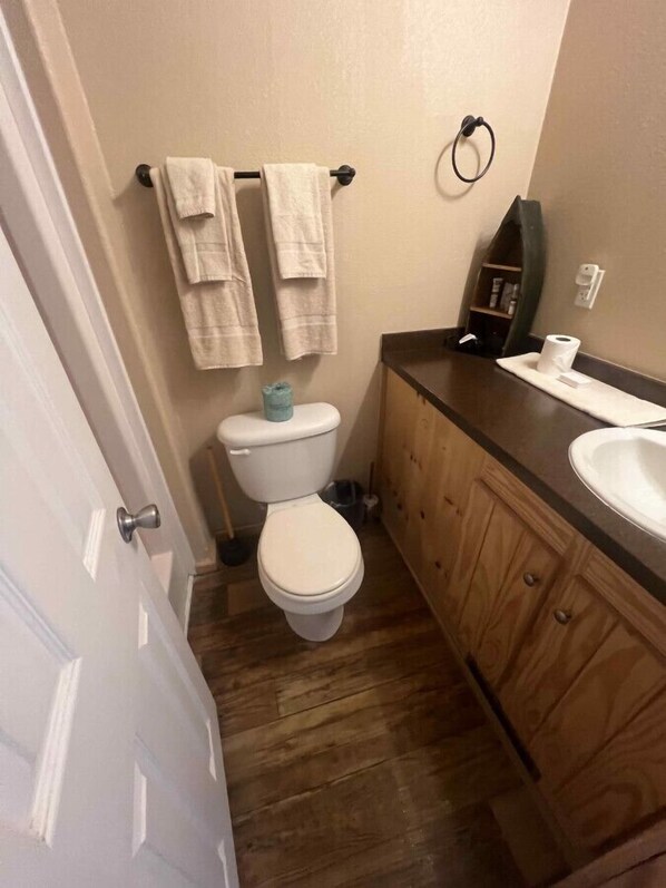 Een badkamer met een toilet, een houten wastafelmeubel en een handdoekrek.