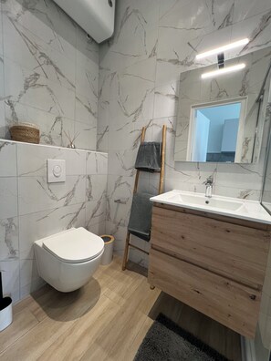 Une salle de bain moderne avec des toilettes, un lavabo et un miroir.
