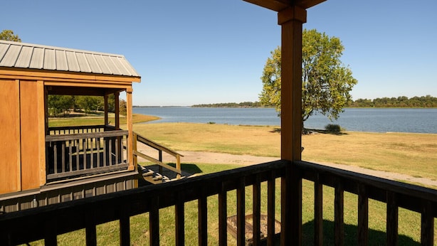 Une terrasse en bois offrant une vue sur un lac et des arbres au loin.