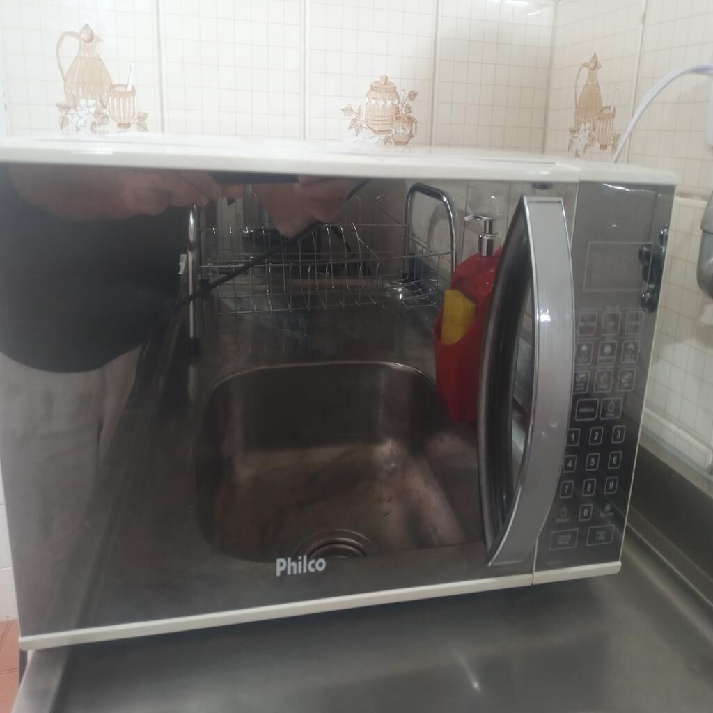 A compact kitchen with a built-in microwave and sink.