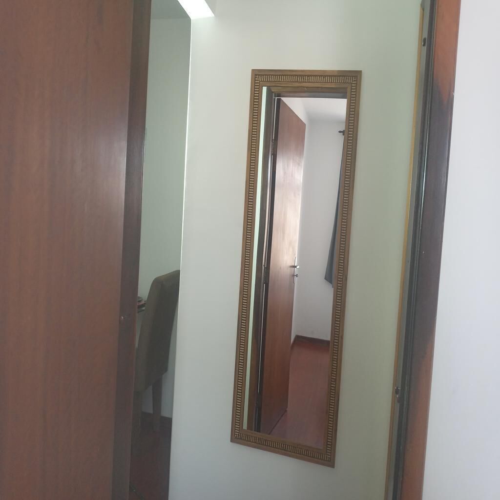 Ein Zimmer mit Holztür, einem Spiegel mit Zierrahmen und einer hellen Wand.