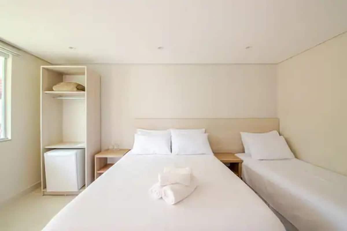 Ein Hotelzimmer mit einem großen Bett, zwei Nachttischen, einem Kleiderschrank und einem kleinen Schreibtisch.