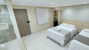 Habitación de hotel con dos camas, un armario, un escritorio y una pizarra en la pared.
