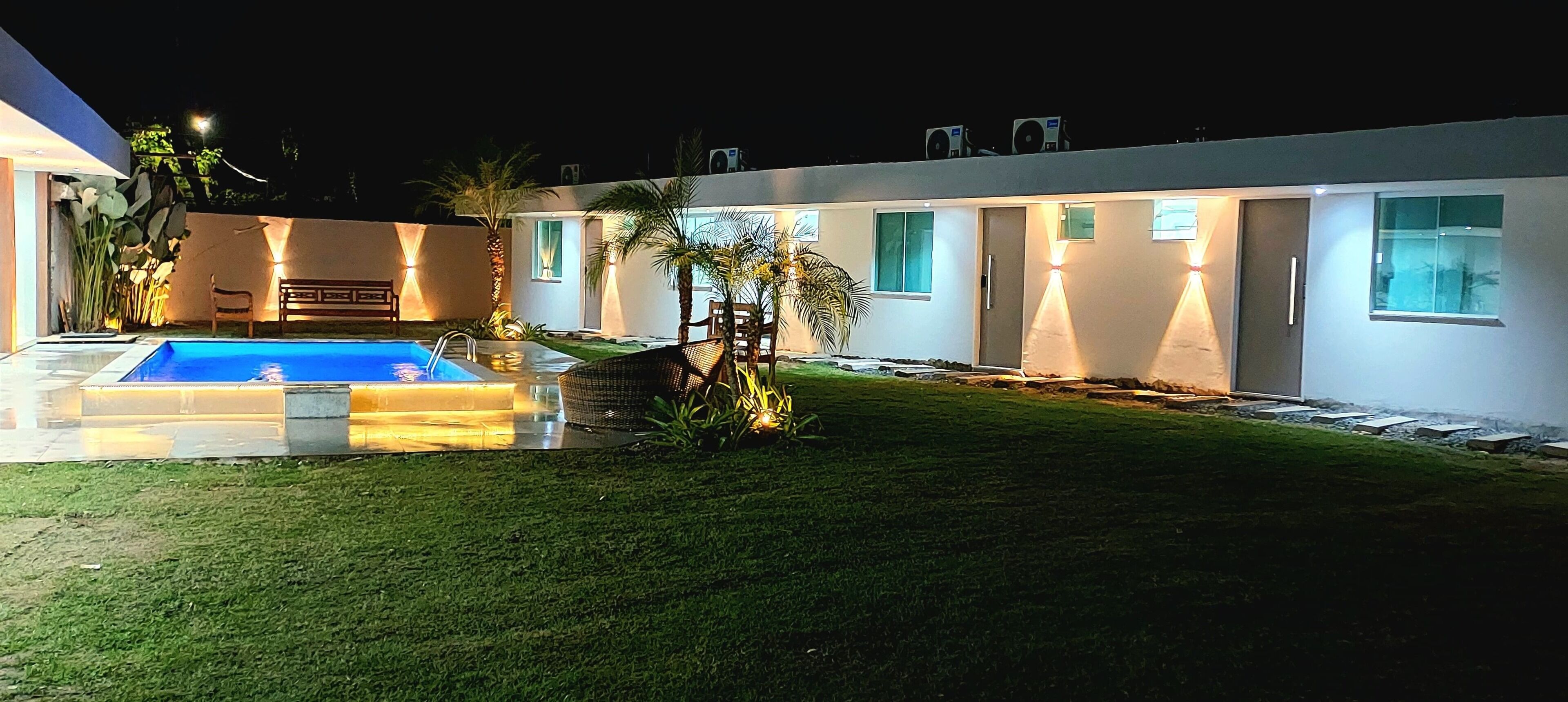 A modern house with a swimming pool, a well-maintained lawn, and outdoor seating.