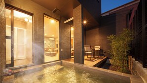 A modern spa area with a hot tub, wooden deck, and a small garden. - Sanwa sen (Beppu)