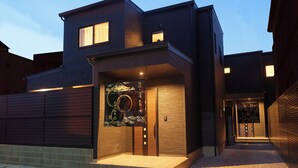 A modern building with a prominent entrance, a small porch, and a decorative wall. - Sanwa sen (Beppu)