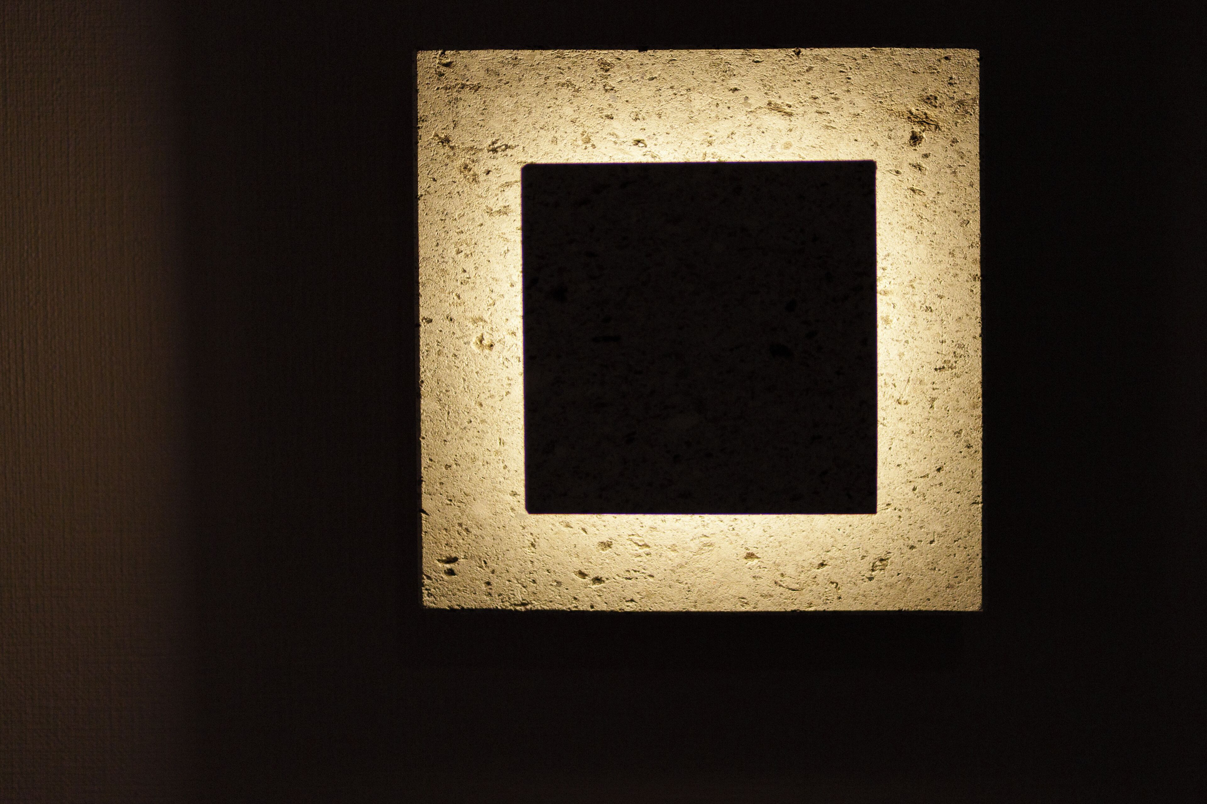 A framed picture with a textured border, mounted on a wall.