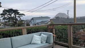 Un canapé bleu clair avec des coussins, placé sur une terrasse en bois et entouré d’une clôture en métal.