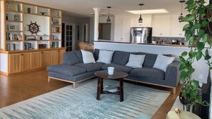Un salon moderne avec un canapé d’angle, une table basse et une bibliothèque.