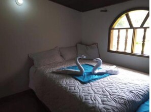 Cozy retreat with a single bed, white comforter, and a window overlooking lush greenery.