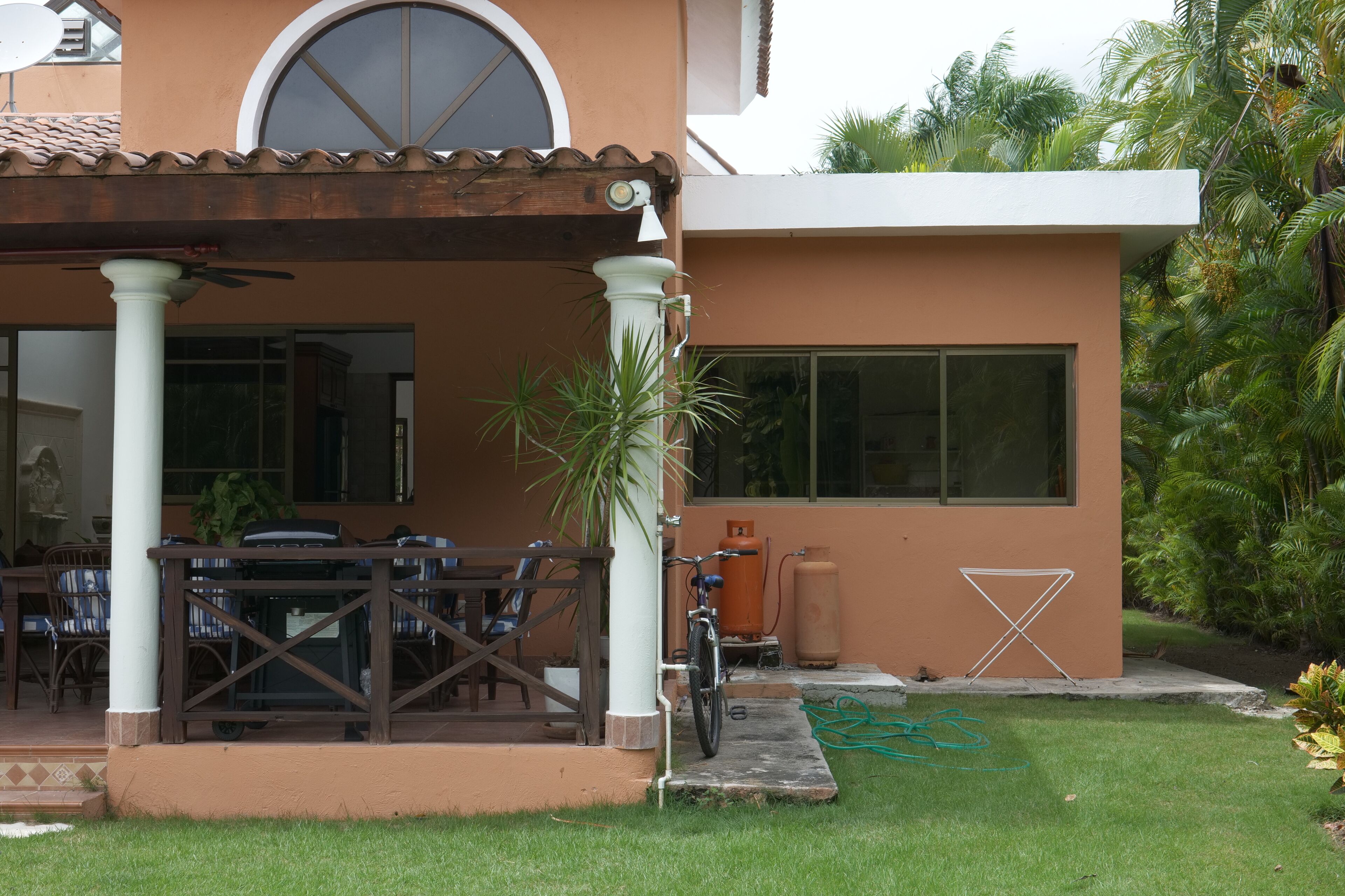 Une maison avec un patio couvert, un vélo et une pelouse.