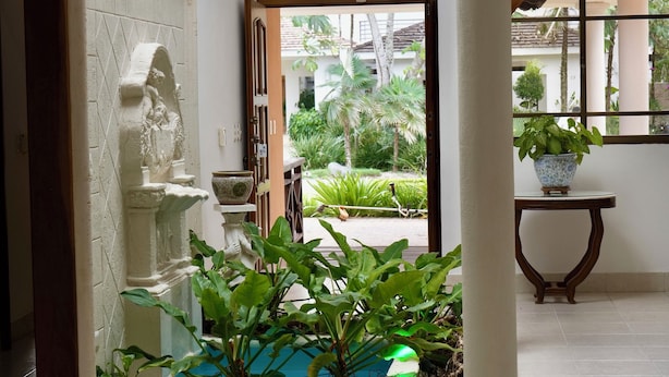 Amplia sala de estar con vista a un jardín, una pared decorativa blanca y una mesa con una planta.