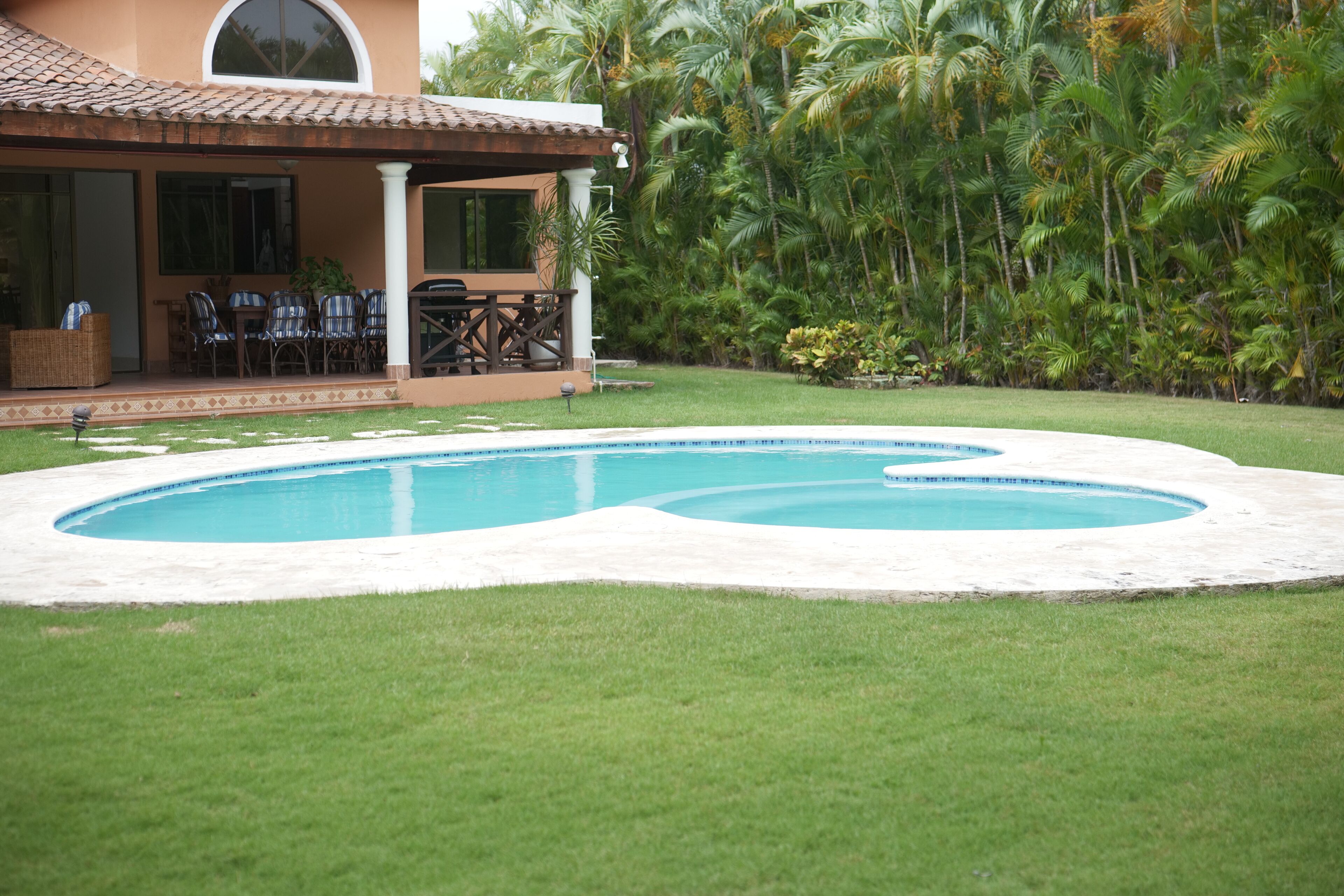 Une piscine avec un espace patio et un coin salon abrité.