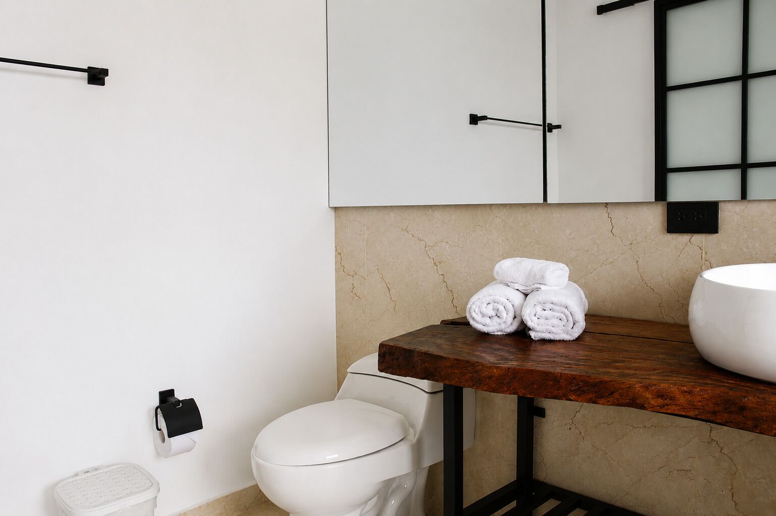 Ein Badezimmer mit Toilette, Waschbecken, Handtuchhalter und Marmorwand.