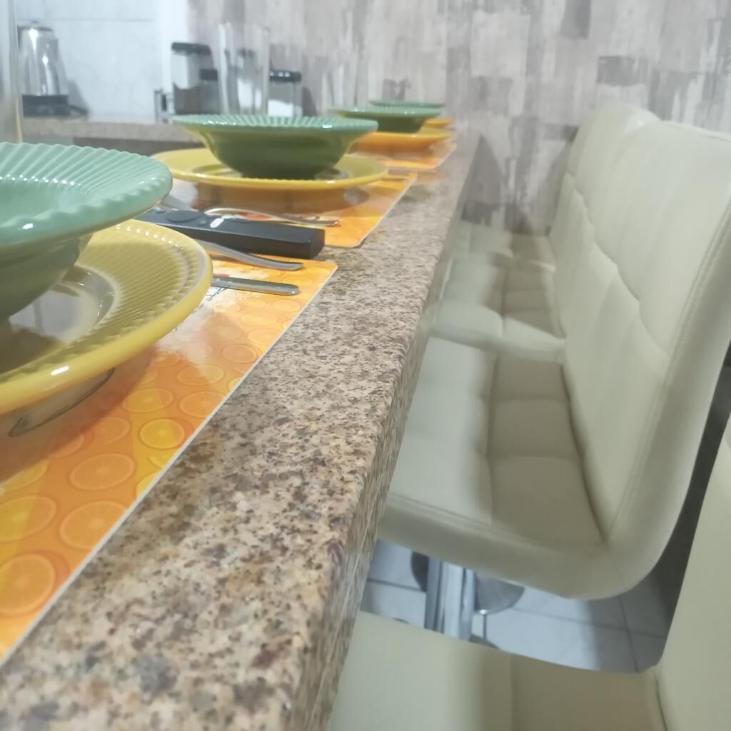 Uma bancada de cozinha com vários pratos verdes e amarelos, uma cafeteira e um micro-ondas.
