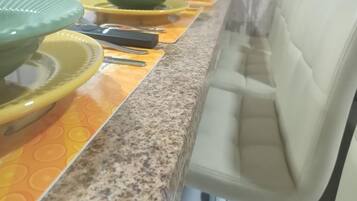 Uma bancada de cozinha com vários pratos verdes e amarelos, uma cafeteira e um micro-ondas.