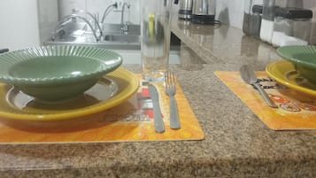 A kitchen with granite countertops, a coffee maker, and a glass of water on the counter.