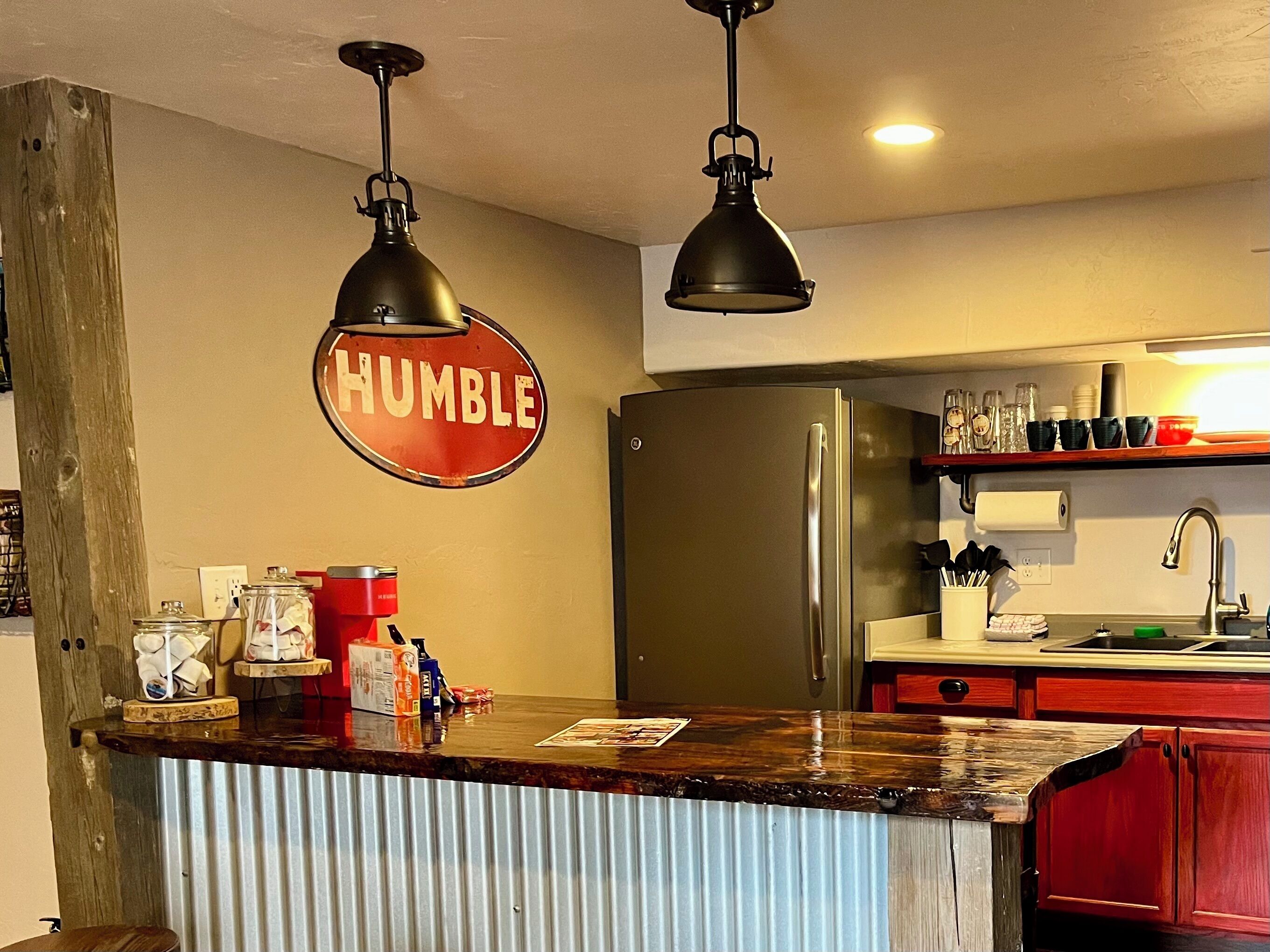 A kitchen with a stainless steel refrigerator, a wooden countertop, and a sign that reads 'HUMBLE'.