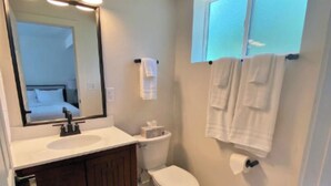 Een badkamer met een grote spiegel, een wastafel, een toilet en een kast met handdoeken.