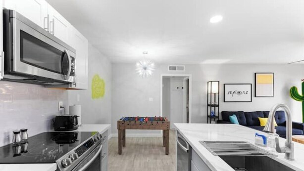 A modern kitchen with a foosball table, a microwave, and a stove. - Modern, stylish condo in Sun Devil Country
 (Tempe)