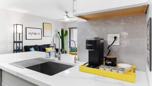 A modern kitchen with a black sink, a coffee machine, and a tray of sugar containers. - Modern, stylish condo in Sun Devil Country
 (Tempe)