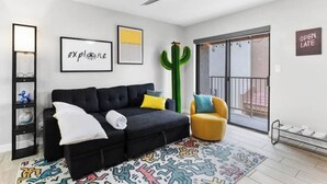 A modern living room with a black sofa, a yellow armchair, a cactus decoration, and a colorful rug. - Modern, stylish condo in Sun Devil Country
 (Tempe)