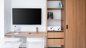 A modern room with a flat-screen TV, a desk with a computer, and a wardrobe with shelves. - Nuevetres by Wynwood House (Bogotá)