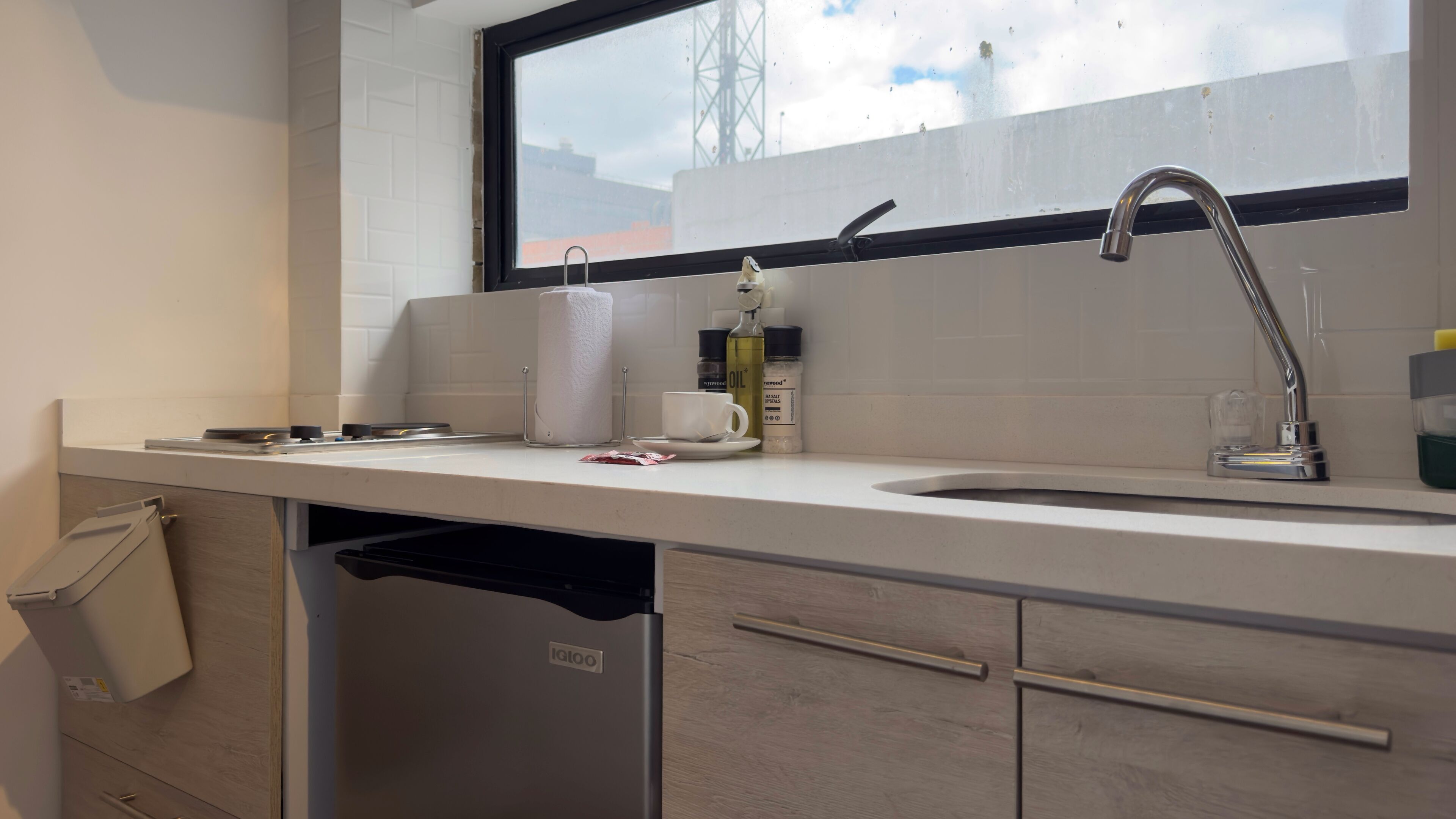 A modern kitchen with a white countertop, stainless steel sink, and a window above the sink.