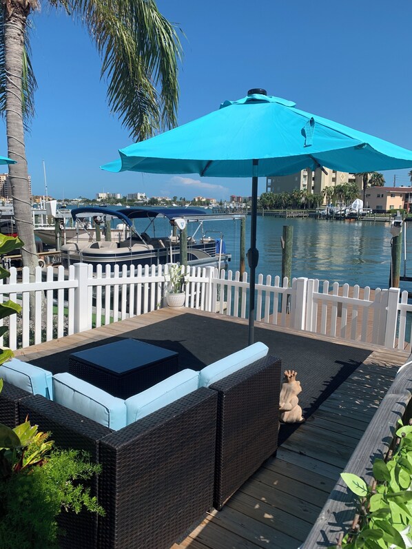 A deck with outdoor seating, a view of the marina, and a white picket fence.